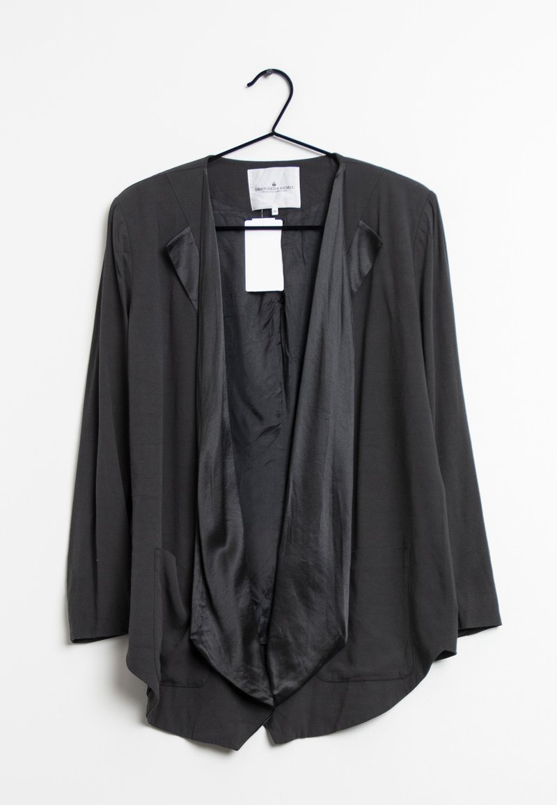 Veste noire à coupe ample avec un devant drapé, des manches longues et deux poches avant. Fabriquée en tissu doux, avec une étiquette à l'intérieur.