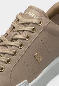 Baskets en cuir texturé beige avec des lacets beige, des œillets dorés, un emblème "B" doré sur le côté et une semelle blanche.