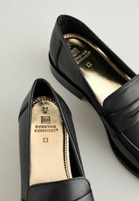 Sorte læder loafers med rund tå, med en guld indersål mærket "FOREVER COMFORT" og subtile syninger. Størrelse 6,5.