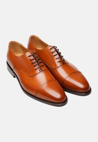 Braune Leder-Dressschuhe mit polierter Oberfläche, spitzer Zehenform, Schnürdesign und subtilen Nähdetails an den Seiten.