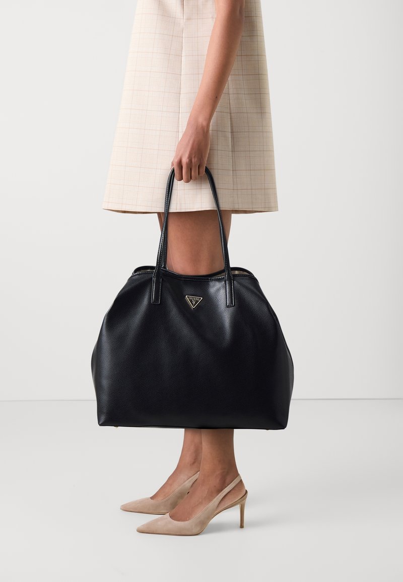 Borsa tote nera in pelle con una forma spaziosa e morbida e superficie texturizzata. Caratterizzata da manici doppi e un accento del logo del marchio triangolare.