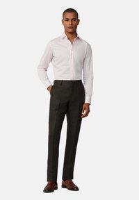 Camicia button-up a maniche lunghe rosa chiaro abbinata a pantaloni grigi scuri. L'outfit presenta linee pulite e una vestibilità su misura, completato da scarpe marroni.
