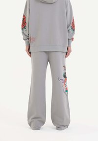 Grå bomullsfleece-set som består av en hoodie med röd ros grafik på ärmen och matchande sweatpants med färgglada tryckdetaljer.