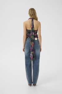 Top a halter fiorito con una lunga cravatta sul retro, motivo nero e viola, abbinato a jeans blu a vita alta, texture di denim, vestibilità comoda.