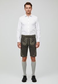 Tummanharmaat lederhosenit, joissa on brodeerauksia, on yhdistetty valkoiseen napitettavaan paitaan, harmaisiin polvisukkiin ja mustiin kenkiin. Varusteisiin kuuluu vyö, jossa on pyöreä solki.
