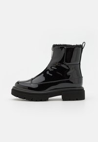 Bottines en cuir verni noir avec un col en fausse fourrure, fermeture éclair sur le côté et semelle en caoutchouc épaisse avec un motif texturé pour une meilleure adhérence.