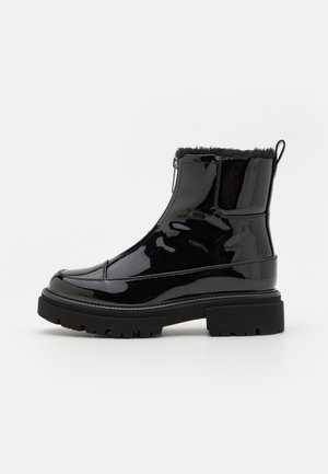 Sorte patentlær ankle boots med kunstpelskrage, sidelukking og chunky gummisåle med tekstur for bedre grep.