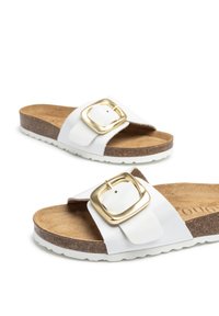 Weiße Sandalen mit einem breiten Riemen und einer goldenen quadratischen Schnalle, einem Korkfußbett und einer strukturierten Gummisohle.