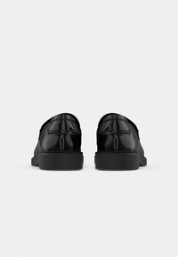 Chaussures en cuir noir avec une finition brillante, bout arrondi, petit talon et coutures décoratives à l'arrière. Design simple et épuré.