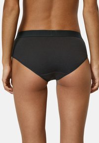 Slip in tessuto a costine nero con una cintura liscia, caratterizzato da un taglio a vita media e bordi senza cuciture per comfort e una vestibilità aderente.