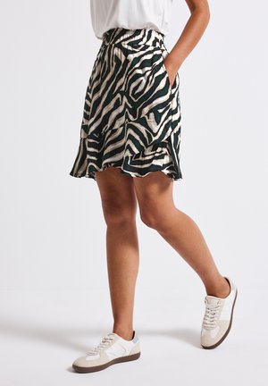 Grøn og creme zebra-stribet nederdel med elastisk talje, flagrende form og lommer, parret med hvide og beige sneakers.