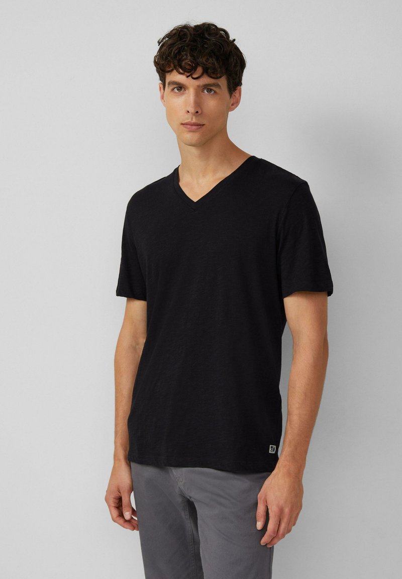 Czarny T-shirt z dekoltem w serek, wykonany z miękkiego materiału, z krótkimi rękawami i luźnym krojem. Posiada małe logo na dolnym brzegu.