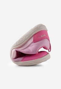 Chaussure de sport rose flexible pliée en deux pour montrer la semelle souple et la tige en maille respirante avec languette de traction et étiquette de marque sur le talon.