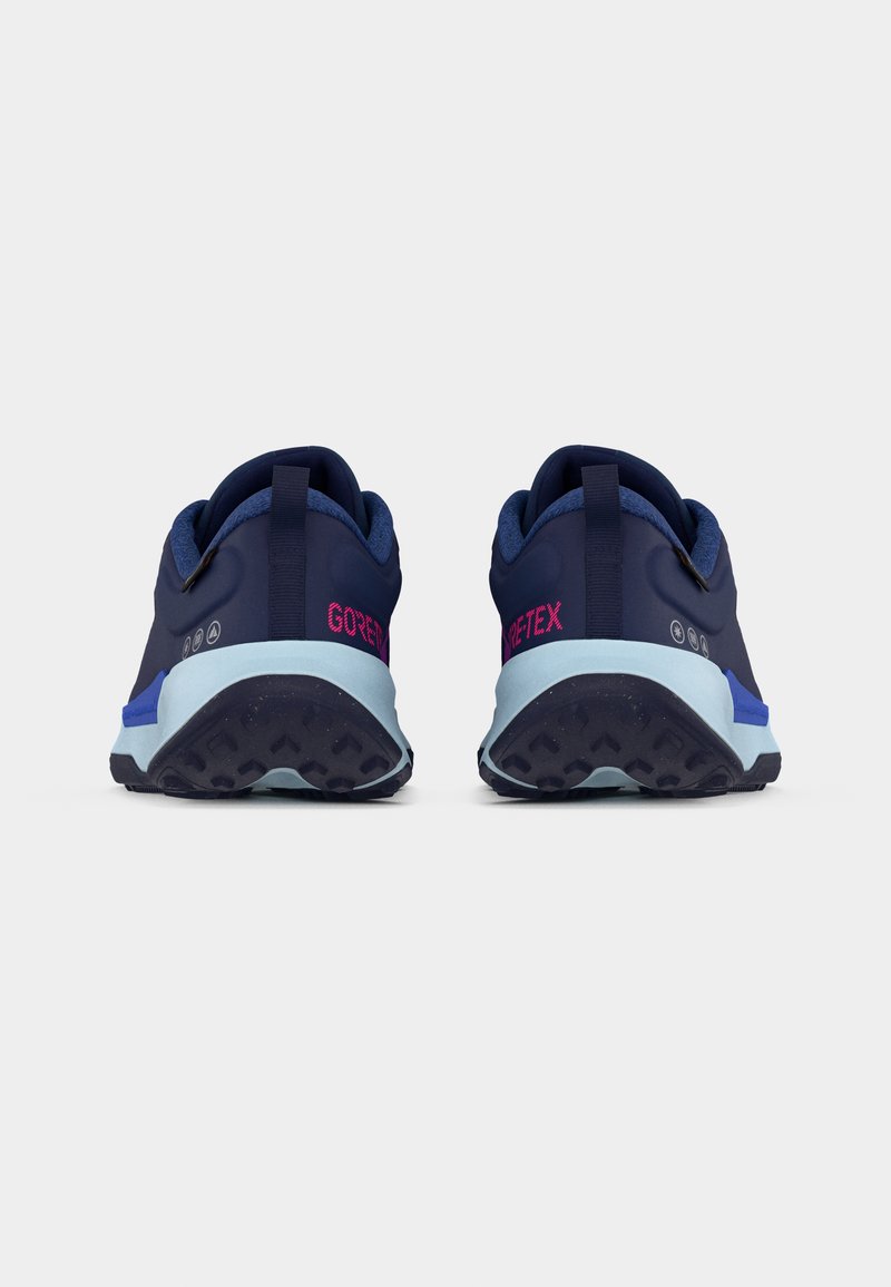 Par de zapatillas Gore-Tex azul marino mostradas desde atrás con entresuelas azul claro y suelas exteriores negras texturizadas sobre un fondo blanco.