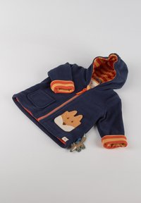 Giacca in pile blu navy con foderatura a righe arancioni, applicazione di una volpe sulla tasca e polsini a righe. Caratterizzata da una zip frontale e cappuccio.