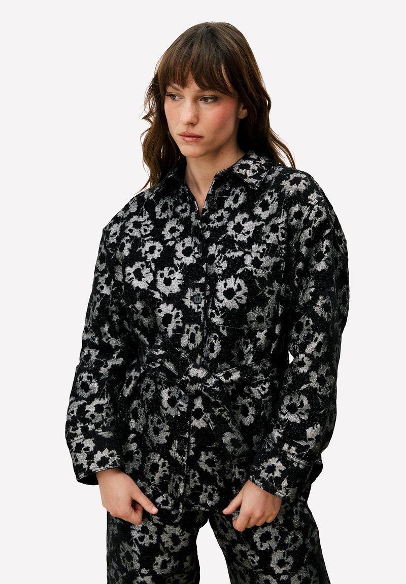 Zwart en zilver bloemmotief overhemd met een kraag en lange mouwen. Voorzien van een tailleband en een gestructureerde stof.