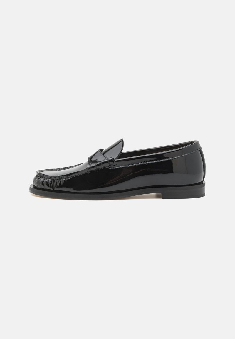 Black patent leather loafers with a rounded toe, decorative stitching, and a low profile. Features a smooth, glossy finish.