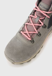 Szare buty trekkingowe z różowymi sznurówkami, prezentujące teksturowany materiał i solidną podeszwę. Logo marki jest widoczne z boku.