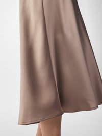 Een taupe satijnen rok met een gladde textuur, een lente-delige zoom en een subtiele glans, met een A-lijn silhouet en nette stiksels.