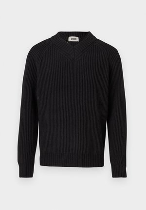 Mustavöinen ribbikudottu neulepaita V-pääntiellä ja pitkillä hihoilla, esiteltynä yksinkertaisella valkoisella taustalla.