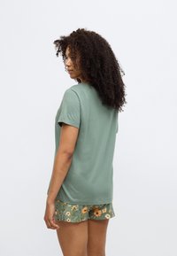 Πράσινο κοντομάνικο μπλουζάκι σε συνδυασμό με σορτς με ανθικό σχέδιο. Απλός, ευθύς σχεδιασμός με μαλακή υφή και άνετη εφαρμογή.