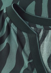 Top in misto cotone caratterizzato da un motivo a strisce zebra verde scuro e nero. Presenta un collo a girocollo testurizzato e una finitura in tessuto liscia.