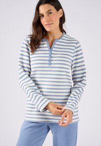 Maglione in pile a righe blu chiaro e bianco, con patta di bottoni, maniche lunghe e una texture morbida. Abbinato a pantaloni in pile blu.