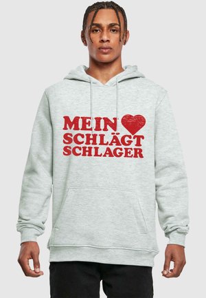 Hele halli kapuutsiga, millel on eest tasku ja julge punane tekst "MEIN ♥ SCHLÄGT SCHLAGER." Kujunduses on reguleeritav kapuuci ja ribakäised.