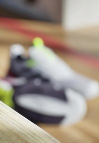 Buty sportowe w odcieniach fioletu i szarości z neonowymi zielonymi akcentami. Skup się na teksturowanej tkaninie, wyraźnych podeszwach i smukłych kształtach.