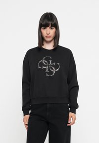 Zwarte sweatshirt met een ronde hals, voorzien van een zilveren glitterslogo in het midden. Zachte textuur en een losse pasvorm met geribde manchetten.