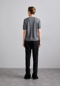 Szürke, rövidujjú pulóver, kerek nyakkivágással, fekete, széles szárú nadrággal párosítva, hátulról bemutatva, semleges háttér előtt.