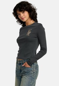 Czarny T-shirt z długim rękawem o dopasowanym kroju i zaokrąglonym dolnym wykończeniem. Na piersi znajduje się złota grafika z motywem zwierzęcym. Wykonany z miękkiej tkaniny.