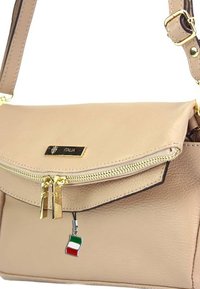 Beige leren schoudertas met gouden rits, verstelbare schouderband, "Italia" label en een hangertje van de Italiaanse vlag in groen, wit en rood.