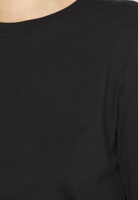 Svart bomull t-shirt med rund halsringning. Mjuk textur, korta ärmar, minimalistisk design, inga synliga logotyper eller mönster.