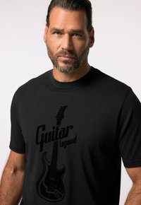 Sort bomulds t-shirt med et guitar grafik og teksten "Guitar Legend" i fede bogstaver. Korte ærmer og rund halsudskæring.