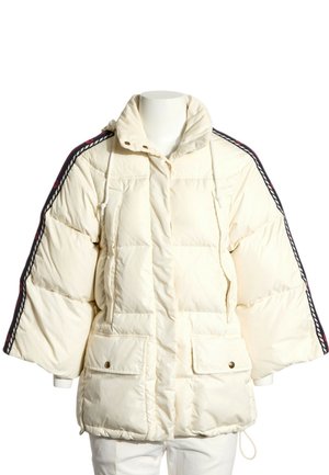 Chaqueta acolchada de color crema con mangas anchas, bolsillos delanteros con solapa, cuello alto y ribete a rayas en negro y rojo en los hombros y mangas.