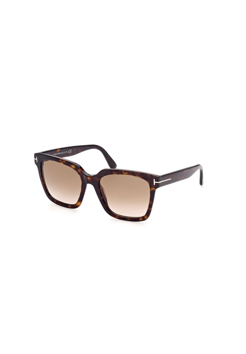 Lunettes de soleil écaille de tortue brunes avec des verres dégradés, forme carrée et accents en argent sur les branches. Fabriquées en matériau plastique.