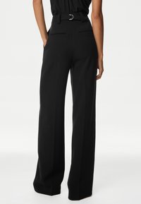 Zwarte, wijde broek met een ceintuur in de taille, dubbele achterzakken en een gladde stofafwerking. Recht gesneden pijpen die tot de grond reiken.