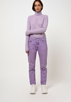 Hellblaues Rollkragensweater aus weichem Material, kombiniert mit hellblauen Jeans. Weiße Sneakers runden das Outfit ab.