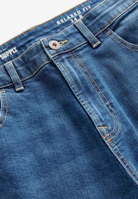 Vaqueros de corte relajado en color azul, confeccionados en denim, con cremallera, botón metálico y costuras en naranja contrastante a lo largo de las costuras.