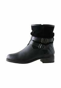 Botas negras hasta el tobillo con un acabado de cuero texturizado, que cuentan con una parte superior de gamuza negra doblada, dos correas decorativas con hebillas y un tacón bajo de madera.