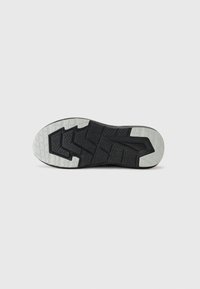 Black sports shoe outsole featuring a textured grip pattern with contrasting white accents along the edges and a geometric tread design.