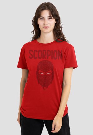 Young woman wearing a red T-shirt with "SCORPION" text and a stylized scorpion mask graphic, standing against a plain background.