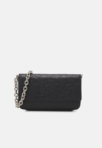 Borsa a pochette in pelle nera con motivo impresso "ck" e tracolla in argento su sfondo bianco.