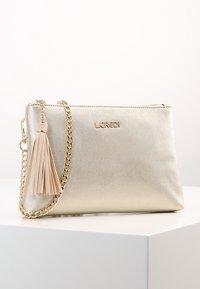 Metallisk guld clutch-taske med en tekstureret overflade. Har en aftagelig kædestrop og en beige frynseaccent. Lynlåslukning øverst.