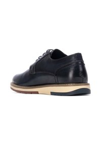 Zapato de cuero azul marino oscuro con puntera redondeada, diseño de cordones y suela de goma color beige claro. Presenta acentos de costura y un detalle en el talón en contraste.