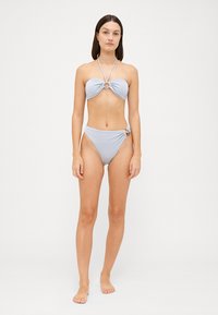 Svetlomodrý bikiny set, ktorý má top s prekrúteným predným dielom s kruhovým akcentom a zodpovedajúce vysoké bikiny s detailom s postranným hardvérom.