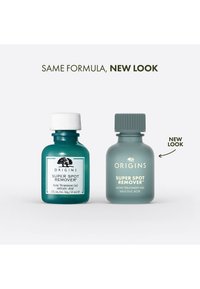 To glassflasker med Origins Super Spot Remover; til venstre: mørk teal med hvit kork, til høyre: frostet grågrønn med teksturert kork, begge med etiketter.