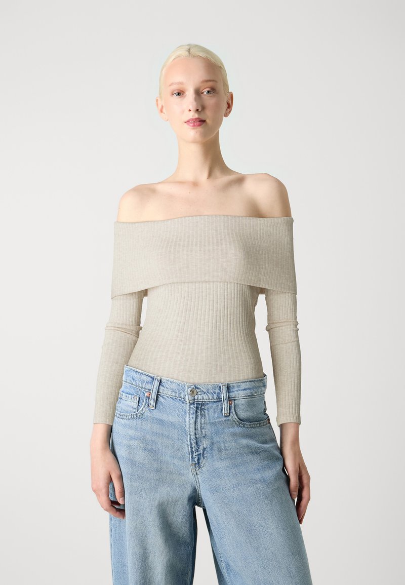 Bež off-shoulder ribiga top pika varrukaga ja tekstureeritud kangaga, kombineeritud helesiniste laiade pükstega klassikaliste taskutega.