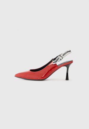 Red patent leather slingback shoe with pointed toe, black heel, and a decorative fabric strap featuring a repeating logo pattern.